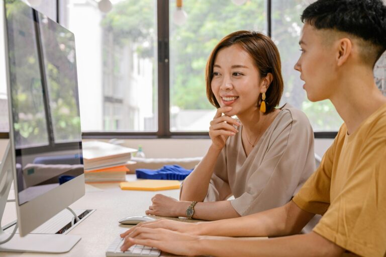 Two people looking at a desktop screen