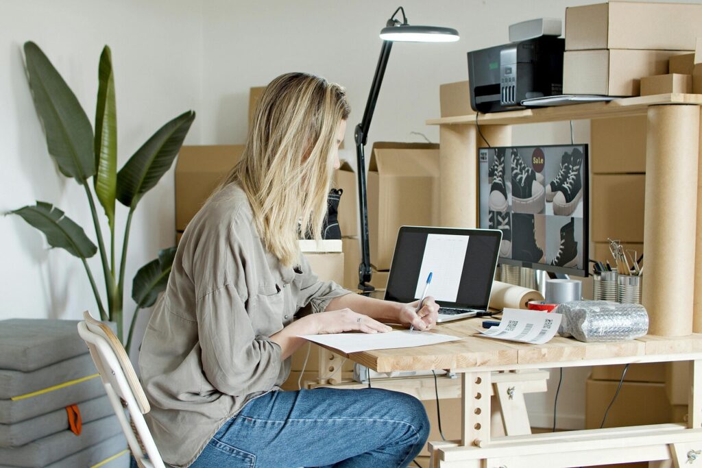 Woman writing on a piece of paper while sitting on her work station